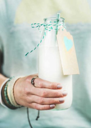 young-woman-holding-bottle-of-dairy-free-almond-PEYHRSZ.jpg